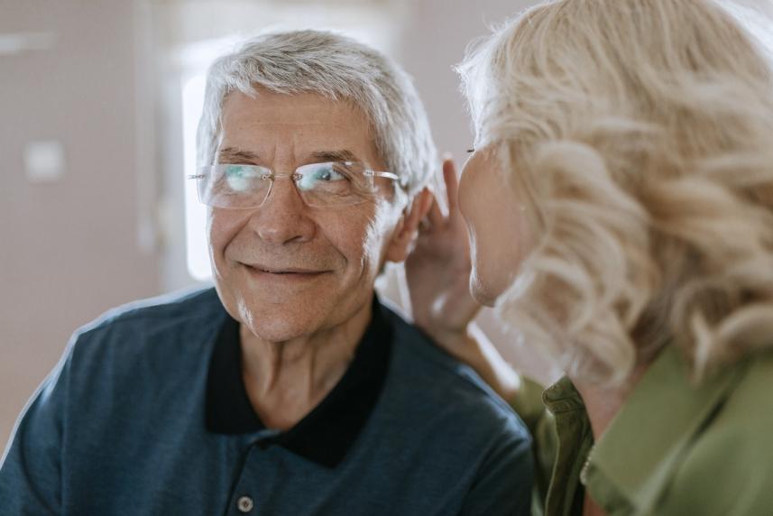 Wife talking to husband with hearing aid in ear