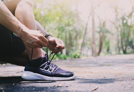 Low Section Of Man Tying Shoelace On Road